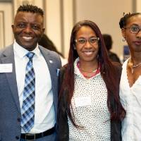 Three event attendees standing together and smiling for camera